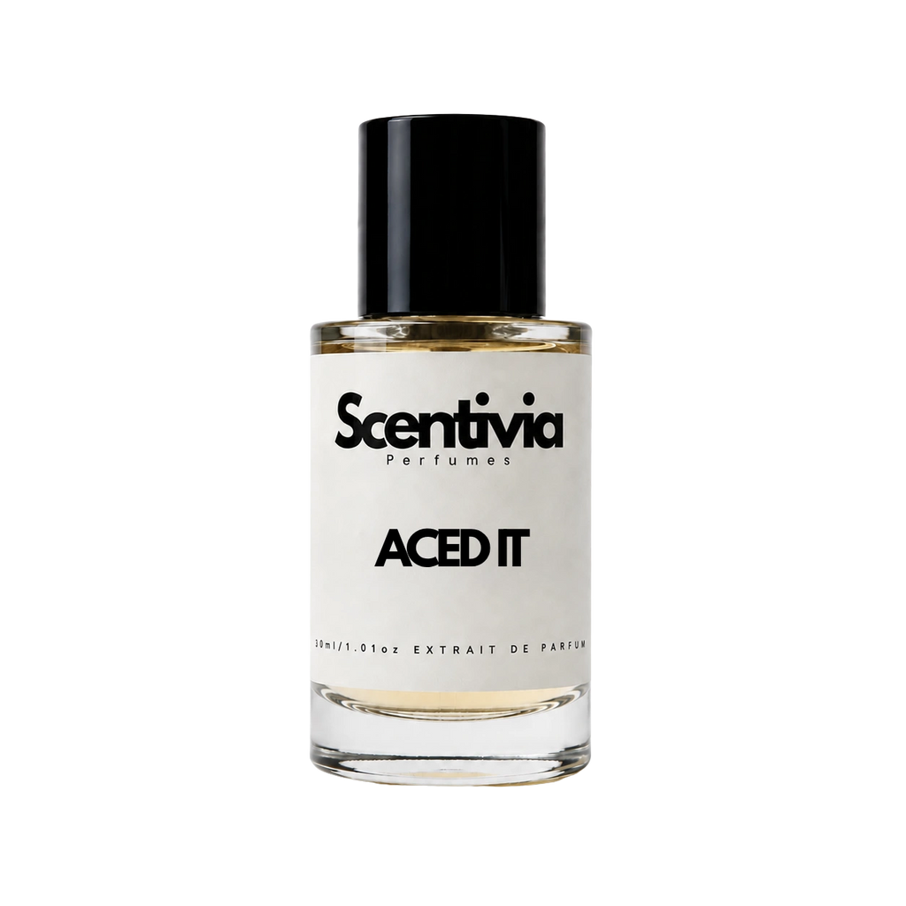 A glass bottle of Scentivia Perfumes 'Aced It' Extrait de Parfum against a black background, featuring a black cap, off-white label, and golden-amber liquid